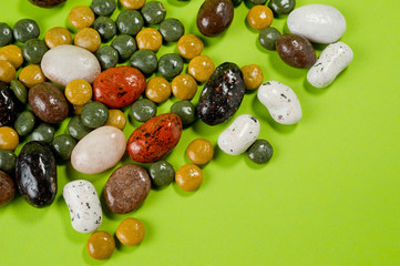 Pebble-dragee with apricots, chocolate, mandarin and marzipan. Tasty, bright, shot on a green background