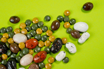 Pebble-dragee with apricots, chocolate, mandarin and marzipan. Tasty, bright, shot on a green background