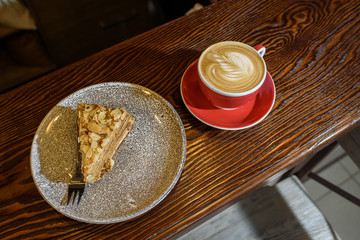 Delicious esterhazy cake with mendala chips and fresh aromatic cappuccino coffee on a wooden table in a cozy coffee shop