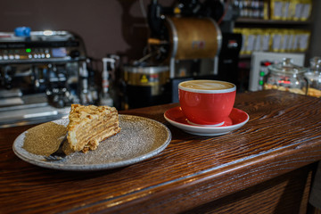 Delicious esterhazy cake with mendala chips and fresh aromatic cappuccino coffee on a wooden table in a cozy coffee shop