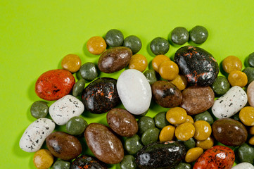 Pebble-dragee with apricots, chocolate, mandarin and marzipan. Tasty, bright, shot on a green background