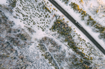 Aerial view on the road and forest at the winter time. Natural winter landscape from air. Landscape in Finland from drone