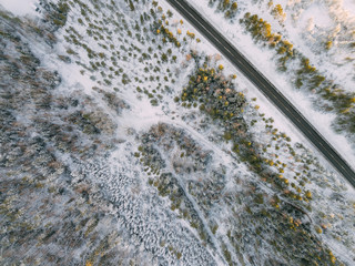 Aerial view on the road and forest at the winter time. Natural winter landscape from air. Landscape in Finland from drone
