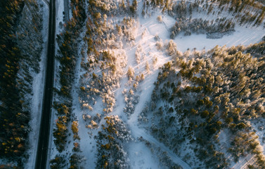 Aerial view on the road and forest at the winter time. Natural winter landscape from air. Landscape in Finland from drone