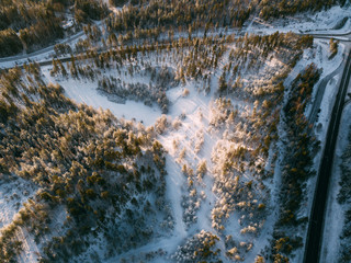 Aerial view on the road and forest at the winter time. Natural winter landscape from air. Landscape in Finland from drone