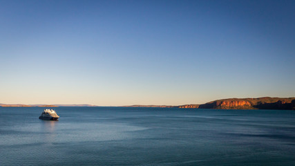 An luxury expedition cruise ship at anchor in the late afternoon in Prince Frederick Harbor on the remote North West Coast of the Kimberley Region of Western Australia.