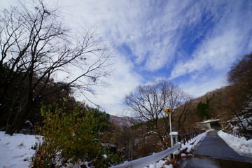 初冬の雪国、道路の水たまりと青空