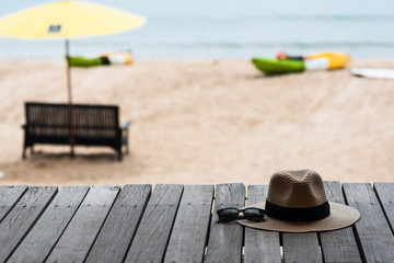 Sunglasses and straw hat on the wooden floor at the beach, summer concept.