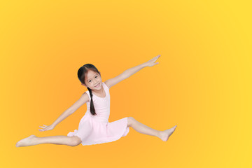 Asian little child girl dancer ballet ballerina stretching isolated on orange-yellow background. Beautiful children in pink tutu skirt.