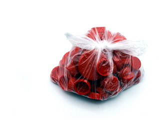 Fototapeta premium Red plastic bottle caps sorted by colors in transparent single use plastic bags. PP an PET pollution.