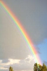 Rainbow on cloudy grey and blue sky background