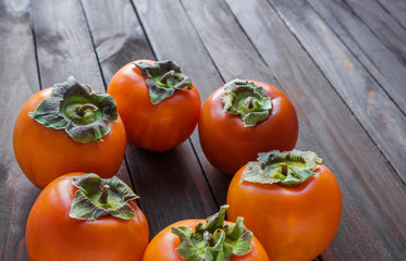 fresh ripe persimmons on brown wooden table 