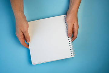 Obraz premium white sheet of Notepad in two hands, copyspace