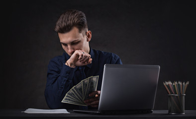 Successful business man on a dark background with laptop and money. Bank Sales Manager