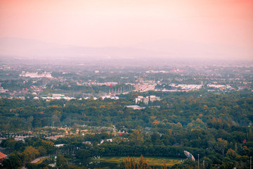 Blurry high angle nature background, which can see distant views (houses, mountains, trees, roads). The atmosphere is surrounded by the wind blowing through, seen at the natural viewpoint on the way.