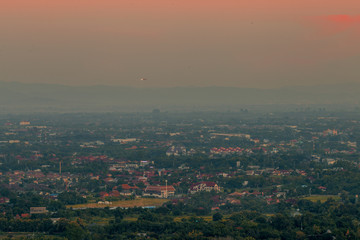 Blurry high angle nature background, which can see distant views (houses, mountains, trees, roads). The atmosphere is surrounded by the wind blowing through, seen at the natural viewpoint on the way.