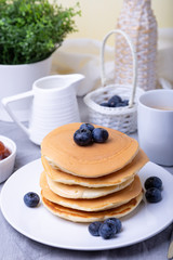 Pancakes with blueberries, cherries and mini apple jam. A cup of coffee and gravy boat in the background. Traditional american pancakes. Close-up.