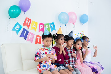 Adorable Asian schoolkids group with beautiful dresses enjoy the birthday party at home with many gift boxes , juices, and bakery