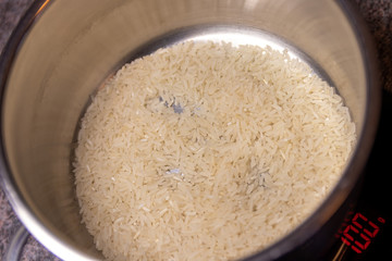 100 gram of white rice in cooking pot on scale