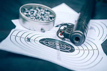 Air rifle, cartridges and paper target on a black background, top view,  sport shooting