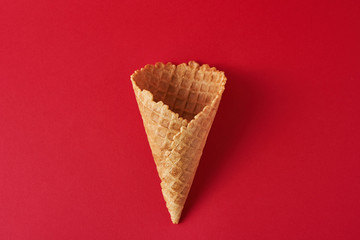 Empty ice cream cone on the red background, top view flat lay. Minimalism style creativity concept