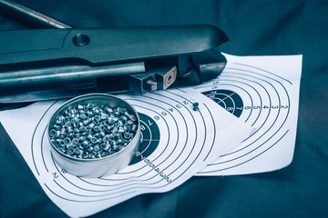 Air rifle, cartridges and paper target on a black background, top view,  sport shooting