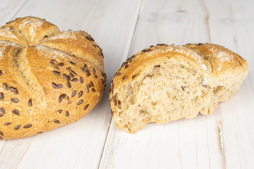 Group of one whole one half of sesame kaiser roll on white wood