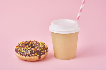 Cup of coffee take away and donut on a pink background