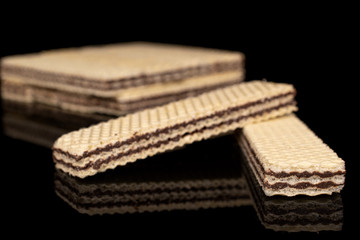 Lot of whole sweet chocolate biscuit wafer two in focus isolated on black glass