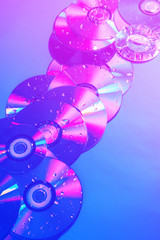 CDs on a plain background illuminated with neon light pink blue, minimal style