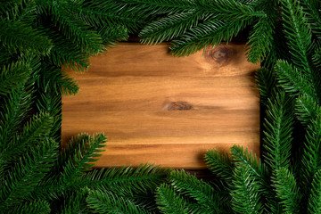 Top view of wooden plate decorated with fir tree branches. New Year dinner concept with empty space for your design