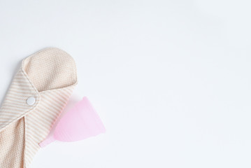 reusable pad and pink menstrual cup on white background. woman period concept. eco friendly flat lay.