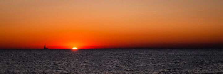 Fototapeta premium Dramatic sunset with sailboat silhouette