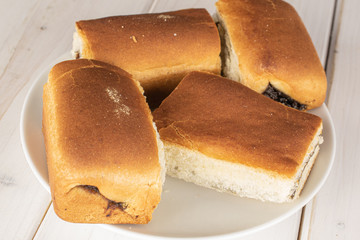 Group of four whole sweet czech bun on white ceramic plate on white wood