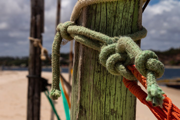 Colored ropes knotted on a pole. Knots at the edge of the sea. Tying and knotting concept.