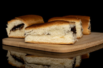 Group of four whole sweet czech bun on bamboo cutting board isolated on black glass