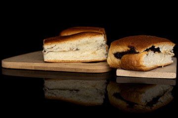 Group of three whole sweet czech bun on bamboo cutting board on wooden cutting board isolated on black glass