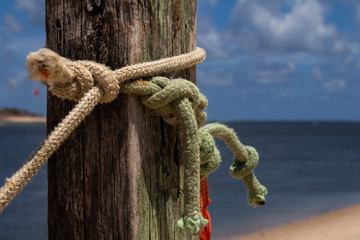 Colored ropes knotted on a pole. Knots at the edge of the sea. Tying and knotting concept.