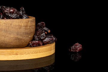 Lot of whole dried cowberry................ in copper bowl on round bamboo coaster isolated on black glass