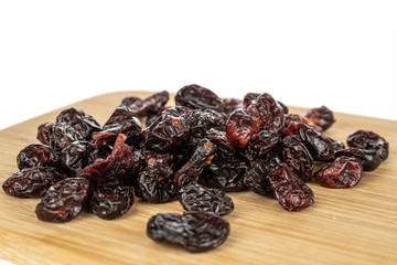 Lot of whole dried cowberry................ on bamboo cutting board isolated on white background