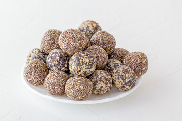 Healthy organic energy bites with nuts, cacao, and honey - sports food, vegetarian raw snack on white background. Copy space