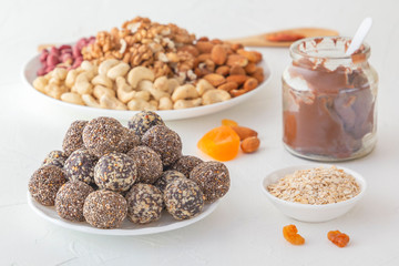 Natural healthy raw energy bites, chocolate paste and mix of dried fruits with nuts on a white table