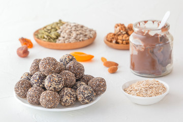 Natural healthy raw energy bites, chocolate paste and mix of dried fruits with nuts on a white table
