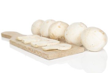 Group of five whole four slices of fresh white champignon on wooden cutting board isolated on white background
