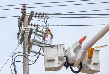 Electrician repairing wire of the power line on electricity power pole  with bucket hydraulic lifting platform