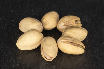 Group of seven whole salted pistachio on grey stone