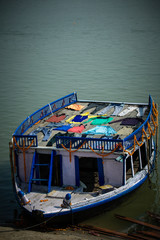 Fototapeta na wymiar Old boat on the river ganges with colorful clothes drying on upper deck.