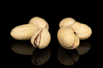 Group of six whole salted pistachio isolated on black glass