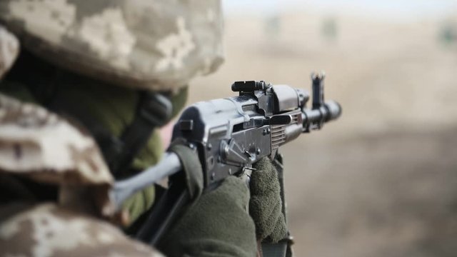 Soldier gunning from AK 74 in khaki uniform in a range in slow motion