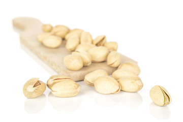 Lot of whole salted pistachio on wooden cutting board isolated on white background